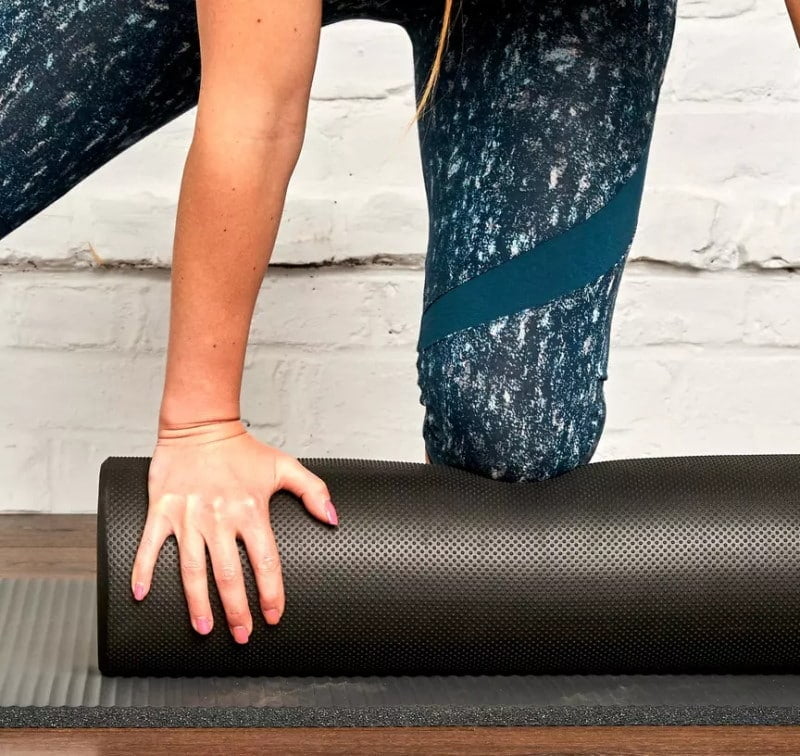 Une femme qui utilise un Foam Roller pour la pratique du Pilates